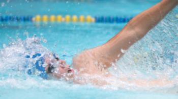 Ein Schwimmer mit blauer Badekappe beim Kraulschwimmen in einem Schwimmbecken